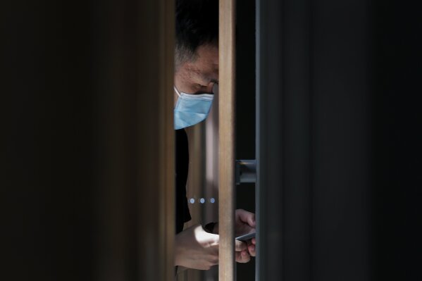 A man wearing a face mask to protect against the new coronavirus opens his health code on his smartphone before entering a cafe at a shopping district in Beijing, Sunday, July 19, 2020. China on Sunday reported another few dozen of confirmed cases of the coronavirus in the northwestern city of Urumqi, raising the total in the country's most recent local outbreak to at least 30. (AP Photo/Andy Wong)