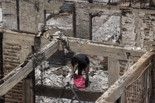 A resident cleans up ashes and debris from a home burned down by a forest fire, in Vina del Mar, Chile, Sunday, Feb. 4, 2024. (AP Photo/Cristobal Basaure)