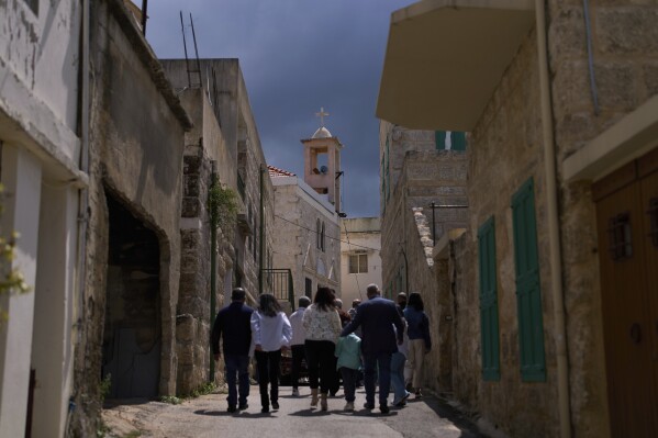 Worshippers walk to Saint Mary Greek Melkite Church, background, to attend the traditional Palm Sunday procession in Quraye, near the southern port city of Sidon, Lebanon, Sunday, April 13, 2025. (AP Photo/Hassan Ammar)