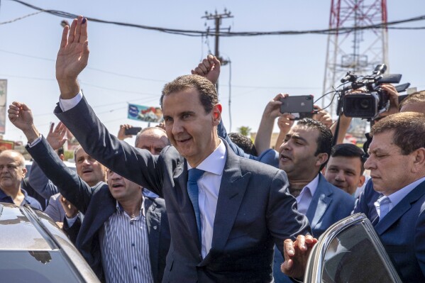 ARCHIVO - El presidente de Siria, Bashar Assad, en el centro, saluda a sus seguidores en un centro de votación durante las elecciones presidenciales en la localidad de Douma, en la región oriental de Ghoutta, cerca de la capital siria, Damasco, en Siria, el 26 de mayo de 2021. Assad viajó a China en su primera visita a Beijing desde que comenzó el conflicto en su país hace 12 años. (AP Foto/Hassan Ammar, Archivo)