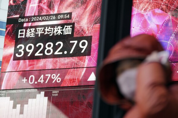 A person walks in front of an electronic stock board showing Japan's Nikkei 225 index at a securities firm Monday, Feb. 26, 2024, in Tokyo. Asian shares mostly declined Monday, although Tokyo's benchmark Nikkei 225 index touched another record high in morning trading. (AP Photo/Eugene Hoshiko)