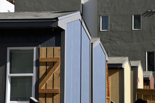 Cabin-like structures are seen at a micro community in Denver on Wednesday, June 5, 2024. Each structure includes a twin bed, desk and closet. The city built three such communities with nearly 160 units total in about six months, at roughly $25,000 per unit, to help ease homelessness. (AP Photo/Thomas Peipert)