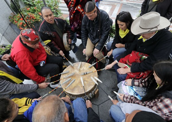 FILE - Native Americans and First Nations people join in on a drum circle during an Indigenous Peoples Day blessing and rally before a march, Oct. 8, 2018, in Seattle. Native American people will celebrate their centuries-long history of resilience on Monday, Oct. 9, 2023, through ceremonies, dances and speeches. The events across the United States will come two years after President Joe Biden officially commemorated Indigenous Peoples Day. (AP Photo/Elaine Thompson, File)