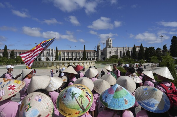 A group of Vietnamese from the United States travelling to attend International World Youth Day stand in front of the 16th century Jeronimos monastery in Lisbon, Tuesday, Aug. 1, 2023. Pope Francis will visit the monastery when he arrives Aug. 2 to attend the event that is expected to bring hundreds of thousands of young Catholic faithful to Lisbon and goes on until Aug. 6. (AP Photo/Ana Brigida)