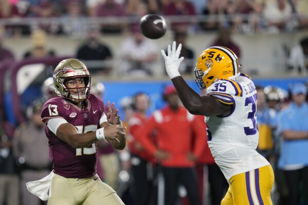 Florida State quarterback Jordan Travis (13) throws a pass as he is pressured by LSU defensive end Sai'vion Jones (35) during the first half of an NCAA college football game Sunday, Sept. 3, 2023, in Orlando, Fla. (AP Photo/John Raoux)
