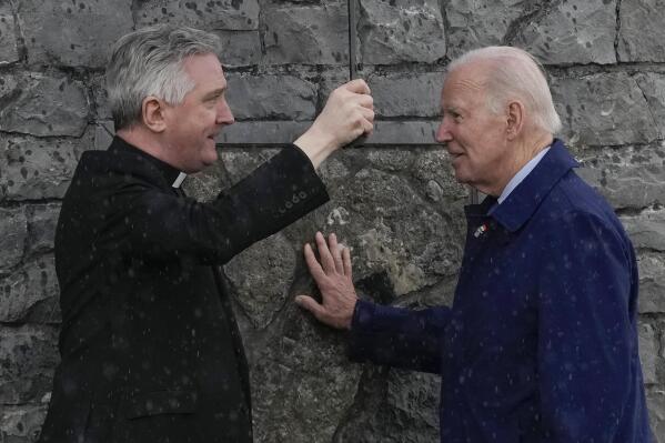 President Joe Biden touches part of the original stonework from the apparition gable at the Knock Shrine as he talks with Father Richard Gibbons, parish priest and rector of Knock Shrine, in Knock, Ireland, Friday, April 14, 2023. (AP Photo/Patrick Semansky)