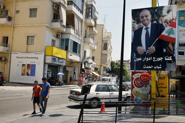 In this Monday, June 24, 2019 photo, a poster shows George Aoun, head of the municipality of the village of Hadat, with Arabic that reads "We are all George Edward Aoun. Hadat youth," in the Christian village of Hadat, where only Christians can rent or buy property, near Beirut, Lebanon. The town's Muslim ban, imposed years ago, has recently sparked a national outcry. The case reflects Lebanon's rapidly changing demographic make-up against the backdrop of deep-rooted sectarian divisions that once erupted into a 15-year civil war. (AP Photo/Bilal Hussein)