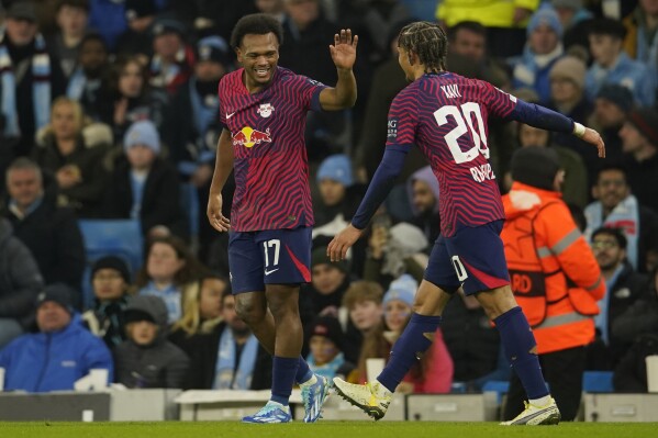 Leipzig's Lois Openda, left, celebrates after scoring his side's second goal during the group G Champions League soccer match between Manchester City and RB Leipzig at the Etihad stadium in Manchester, England, Tuesday, Nov. 28, 2023. (AP Photo/Dave Thompson)