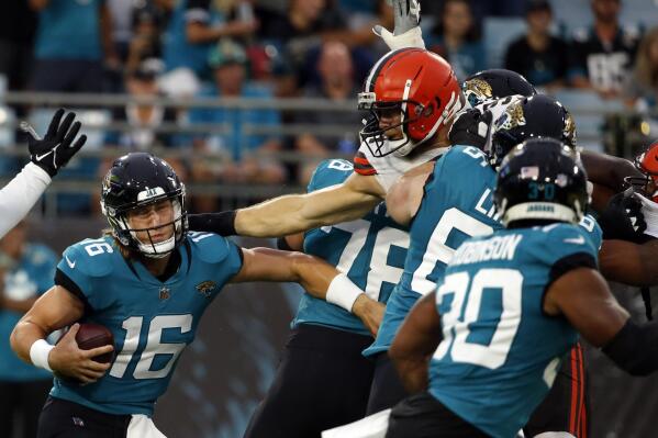 Jacksonville Jaguars quarterback Trevor Lawrence (16) tries to avoid a tackle by Cleveland Browns defenders during the first half of an NFL preseason football game, Saturday, Aug. 14, 2021, in Jacksonville, Fla. (AP Photo/Stephen B. Morton)