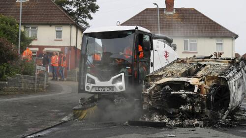 Pracovníci rady okamžitě odklízejí trosky z oblasti kolem zapáleného auta v Ely, Cardiff, úterý 23. května 2023. Desítky mladých lidí házely předměty na policii a zapalovaly auta v pondělí večer v Cardiffu při místních nepokojích, které vypukly o dva roky později .  Mladíci zemřeli při dopravní nehodě.  (PA přes AP)
