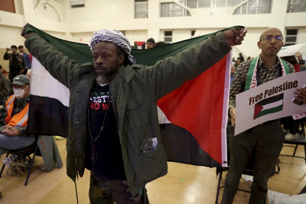 FILE - Jabari Shaw holds a Palestinian flag during an Oakland Unified School District board meeting at La Escuelita Elementary School in Oakland, Calif., on Wednesday, Nov. 8, 2023. The board is considering a resolution calling for a ceasefire between Israel and Hamas. A growing number of Black Americans see the struggle of Palestinians reflected in their own fights for freedom and civil rights. In recent years, the rise of protest movements in the U.S. against police brutality in the U.S., where structural racism plagues nearly every facet of life, has connected Black and Palestinian activists under a common cause. But that kinship sometimes strains the alliance between Black and Jewish activists, which extends back several decades. (Jane Tyska/Bay Area News Group via AP)