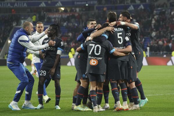 Marseille players celebrate after Lyon's Malo Gusto scored an own goal during the French League One soccer match between Lyon and Marseille at the Groupama stadium, in Decines, near Lyon, France, Sunday, April 23, 2023. (AP Photo/Laurent Cipriani)