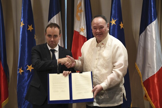 French Minister for the Armed Forces Sebastien Lecornu, left, shake hands with his Philippine counterpart Secretary Gilberto Teodoro as they hold a document during a joint press conference at a hotel in Manila, Philippines on Saturday Dec. 2, 2023. (Ted Aljibe/Pool Photo via AP)