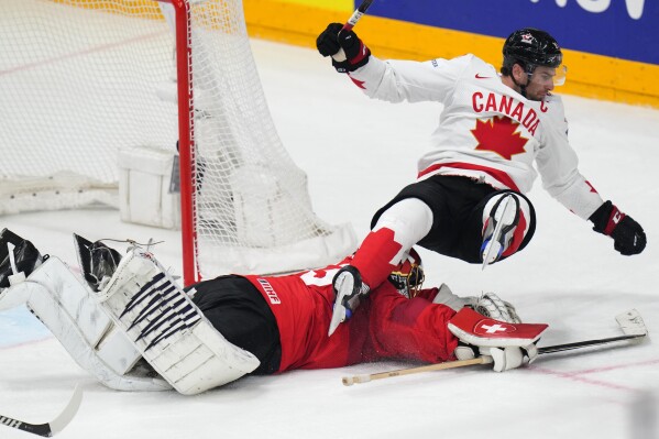 Canada's John Tavares falls over Switzerland's goalkeeper Leonardo Genoni during the preliminary round match between Canada and Switzerland at the Ice Hockey World Championships in Prague, Czech Republic, Sunday, May 19, 2024. (AP Photo/Petr David Josek)