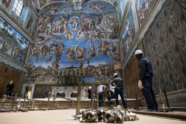 In this image taken on Monday, April 28, 2025, and made available Saturday, May 3, 2025, by Vatican Media, workers prepare the Sistine Chapel at the Vatican, where the upcoming conclave will start May 7, backdropped by Michelangelo Buonarroti's fresco 'The Last Judgement'. (Vatican Media via AP)