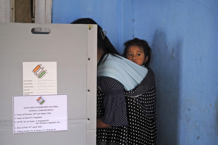 A child looks on from a sling on the back of her mother as she casts her vote during the first round of polling of India’s national election in Chedema village, in the northeastern Indian state of Nagaland, Friday, April 19, 2024. Nearly 970 million voters will elect 543 members for the lower house of Parliament for five years, during staggered elections that will run until June 1. (AP Photo/Yirmiyan Arthur)