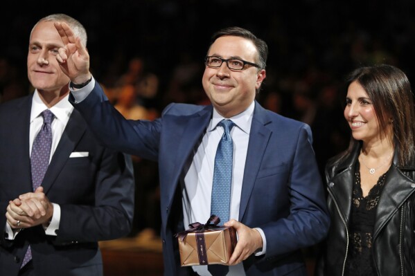 FILE - Broadcaster Ian Eagle, center, waves to the crowd during a ceremony honoring Eagle's 25-year broadcast career at an NBA basketball game between the New York Knicks and the San Antonio Spurs, Thursday, Feb. 21, 2019, in New York. (AP Photo/Kathy Willens, File)