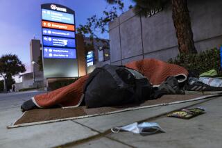 FILE - A homeless person sleeps outside the Los Angeles County+USC Medical Center hospital entrance in Los Angeles, late Wednesday, Dec. 16, 2020. The U.S. government has approved California's overhaul of the nation's largest insurance program for low-income and disabled residents, officials said Wednesday, Dec. 29, 2021, a decision that among other things allows Medicaid money to be spent on housing-related services as the most populous state struggles with homelessness and a lack of affordable housing. (AP Photo/Damian Dovarganes, File)
