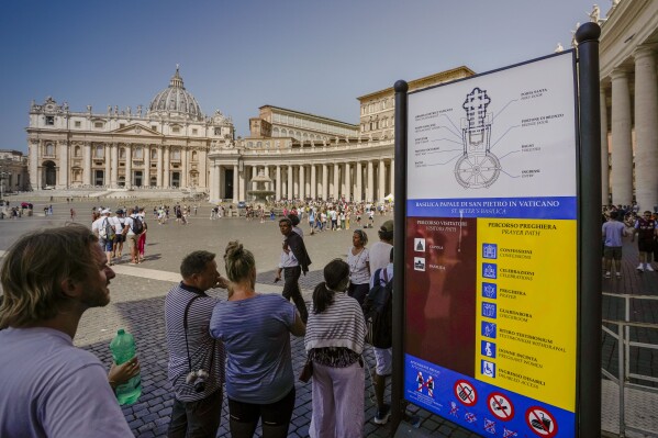A man reads a sign explaining how to enter St. Peter's Basilica for praying or for a touristic visit at The Vatican, Wednesday, July 12, 2023. (AP Photo/Alessandra Tarantino)
