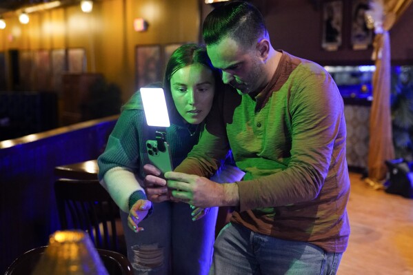 Content creator Jensen Savannah, left, and her fiance and brand manager Jorge Millares, produce a client video at El Puro Cuban Restaurant, Thursday, March 14, 2024, in Charlotte, N.C. (AP Photo/Erik Verduzco)