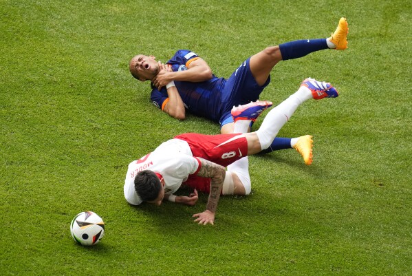 Poland's Jakub Moder, left, and Xavi Simons of the Netherlands lie on the pitch after challenging for the ball during a Group D match between Poland and the Netherlands at the Euro 2024 soccer tournament in Hamburg, Germany, Sunday, June 16, 2024. (AP Photo/Petr Josek)