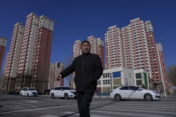 A man walks through a street against a newly completed resident buildings in Beijing on March 1, 2024. China's efforts to restore confidence and rev up the economy will top the agenda during this month’s meeting of the ceremonial national legislature. (AP Photo/Andy Wong)