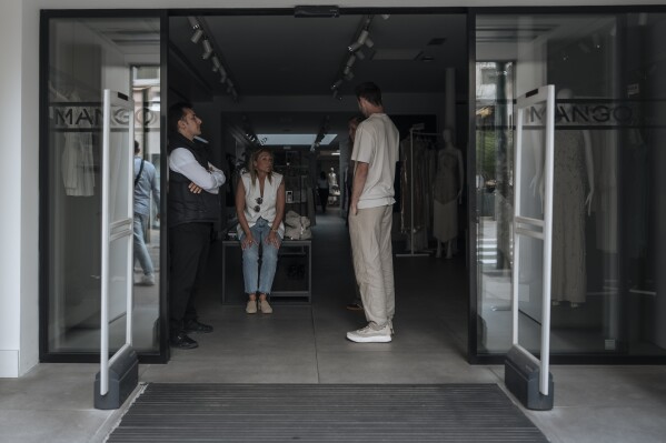 Shop employees wait during an electricity outage in Cannes, southern France, Saturday, May 24, 2025. (AP Photo/Lewis Joly)
