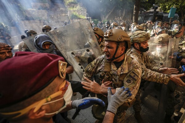 Retired members of the Lebanese security forces and other protesters scuffle with Lebanese army after they removed a barbed-wire barrier in order to advance towards government buildings during a protest in Beirut, Lebanon, Tuesday, April 18, 2023. (AP Photo/Hassan Ammar)