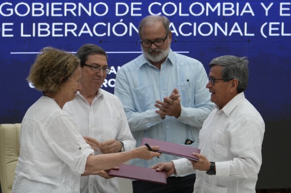 Colombian government representative Vera Grabe, left, and Colombian commander of the National Liberation Army guerrilla group (ELN) Pablo Beltran exchange their signed ceasefire extension agreement in Havana, Cuba, Tuesday, Feb. 6, 2024. Behind are Cuban Foreign Minister Bruno Rodriguez, left, and an unidentified Cuban official. (AP Photo/Ramon Espinosa)