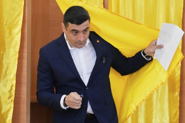 Presidential candidate George Simion exits a voting cabin before casting his vote in the first round of the presidential election redo in Mogosoaia, Romania, Sunday, May 4, 2025. (AP Photo/Vadim Ghirda)