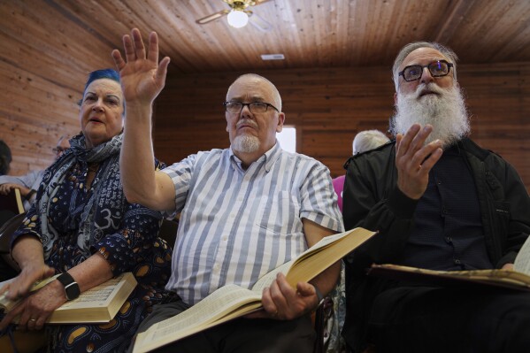 From left, Lisa Bennett, Wade Kotter, and David Stead, Bennett's husband, sing in the alto section during a Sacred Harp singing event at Holly Springs Primitive Baptist Church in Bremen, Ga., on Saturday, March 22, 2025. (AP Photo/Jessie Wardarski)