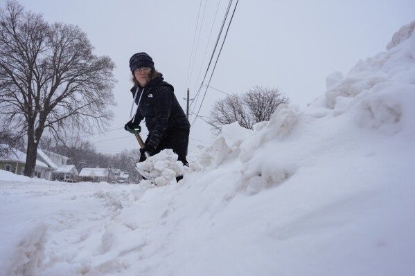 Graphic designer Emily Brewer shovels out her driveway in order to drive to work in Sioux City, Iowa, early on Friday, Jan. 12, 2024. (AP Photo/Carolyn Kaster)