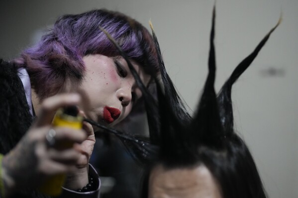 A woman sets a friend's hair during a punk festival in Hangzhou, China, Friday, Jan. 17, 2025. (AP Photo/Aaron Favila)