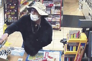 This March 26, 2020 image from surveillance video shows a man, believed to be William Rosario Lopez wearing a surgical mask, with a gun in a Connecticut convenience store.  Just how many criminals are taking advantage of the pandemic to commit crimes is impossible to estimate, but law enforcement officials have no doubt that the numbers are climbing. Reports are starting to pop up across the country, as well as in other parts of the world of crimes that were pulled off in no small part because so many of us are wearing masks. (U.S. District Court of Connecticut via AP)