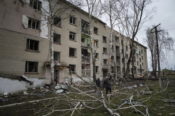 FILE - Local men cut trees in front of a residential building that was heavily damaged by a Russian airstrike in Lukiantsi, Kharkiv region, Ukraine, on Tuesday, April 16, 2024. (AP Photo/Evgeniy Maloletka, File)