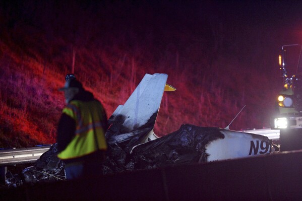 Emergency responders work the scene of a a small plane that crashed on Interstate 26 West, late Thursday, Dec. 14, 2023 near Asheville, N.C. The small plane crashed near Asheville Regional Airport and caught fire Thursday night, but the two people on board escaped life-threatening injuries, authorities said. (Angela Wilhelm /The Asheville Citizen-Times via AP)