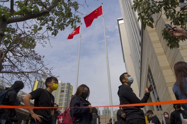 Supporters queue up under a China national flag outside a court as they try to get in for a hearing in Hong Kong Monday, March 1, 2021. People gathered outside the court Monday to show support for 47 activists who were detained over the weekend under a new national security law that was imposed on the city by Beijing last year. (AP Photo/Vincent Yu)