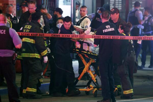 First responders move a shooting victim to an ambulance on Adams Street near State Street in downtown Chicago on Saturday, May 14, 2022. The downtown area saw gun violence and disturbances after a teenage boy was shot and fatally wounded near “The Bean” sculpture in downtown Chicago's Millennium Park (Terrence Antonio James/Chicago Tribune via AP)