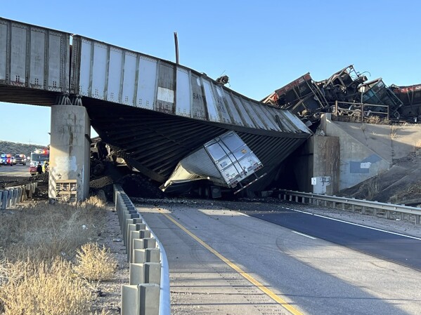 This image provided by the Colorado State Patrol shows a truck caught under a bridge that collapsed during a train derailment across a major highway near Pueblo, Colo., Sunday, Oct. 15, 2023. The main north-south highway in Colorado remained closed Monday morning and the Colorado Department of Transportation said it expected an "extended closure." The truck driver was initially said to be trapped in the Sunday afternoon accident along Interstate 25, but authorities said Monday that he had died. (Colorado Highway Patrol via AP)