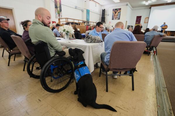 Handler Benjamin Carter looks at his service dog Artemis during a gathering at the San Quentin Rehabilitation Center in San Quentin, Calif., Friday, March 28, 2025. (AP Photo/Eric Risberg)