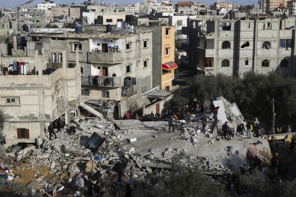 فلسطينيون ينظرون إلى الدمار بعد غارة إسرائيلية على مبنى سكني في رفح، قطاع غزة، الأحد، 3 مارس، 2024. (AP Photo/Hatem Ali)