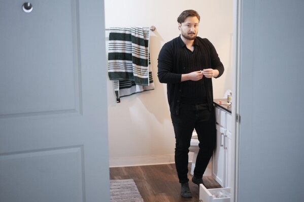 Ashton Colby holds a vial of Testosterone Cypionate Injection in his apartment bathroom in Columbus, Ohio, on Thursday, Jan. 18, 2024. (AP Photo/Carolyn Kaster)