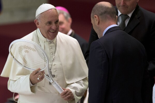 FILE - Pope Francis is presented with a tennis racket by the President of the Italian Tennis Federation Angelo Binaghi, right, during an audience with athletes in the Paul VI hall at the Vatican, Friday, May 8, 2015. Pope Francis congratulated Italy on Monday, Jan. 29, 2024, after tennis player Jannik Sinner became the country's first man to win a Grand Slam singles title, the Australian Open, in nearly a half century. (AP Photo/Alessandra Tarantino, File)