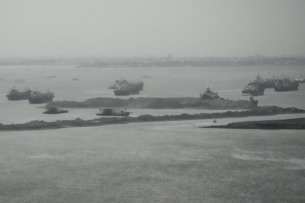 Barges are seen beside reclamation sites in the rain in Manila bay, Philippines on Wednesday, Aug. 2, 2023, The United States expressed concerns over major reclamation projects near its heavily secured embassy, which sits on one edge of Manila Bay, due to the involvement of a blacklisted Chinese company, the U.S. Embassy said Wednesday. (AP Photo/Aaron Favila)