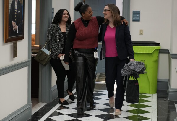 U.S.-Rep.-elect Sarah McBride, D-Del., right, is greeted by Alexis Wrease, Delaware Senate majority deputy communications director, center, and Jenna Greenlee, Delaware Senate majority digital communications specialist, left, as she arrives for her last day as a Delaware state senator at the Delaware Legislative Hall in Dover, Del., Monday, Dec. 16, 2024. (AP Photo/Carolyn Kaster)