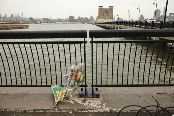 Flowers rest at the end of a pier, Friday, April 11, 2025, near the site where a sightseeing helicopter crashed a day earlier into the Hudson River in Jersey City, N.J. (AP Photo/Yuki Iwamura)