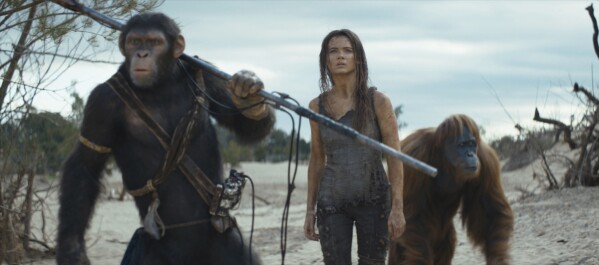 This image released by 20th Century Studios shows Noa, played by Owen Teague, from left, Freya Allan as Nova, and Raka, played by Peter Macon, in a scene from "Kingdom of the Planet of the Apes." (20th Century Studios via AP)