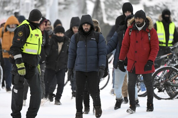 Finnish border guards escort migrants at the Finnish-Russian border crossing in Sala, Finland, Thursday, November 23, 2023 (Jussi Nukari/Lehtikuva, Associated Press)