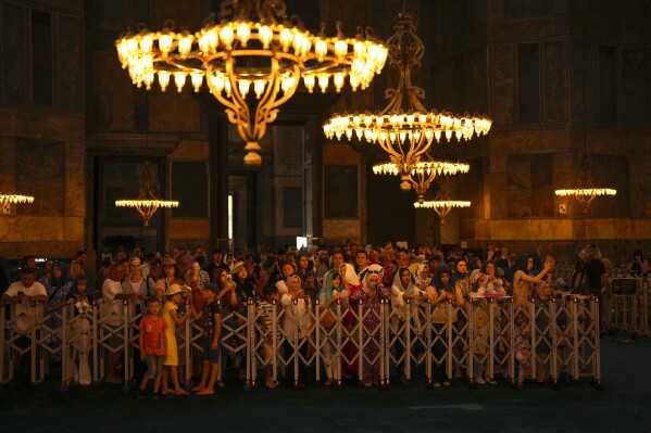 Tourists stabd behind a fence, visit the Hagia Sophia mosque in Istanbul, Turkey, Tuesday, July 4, 2023. Crowds are packing the Colosseum, the Louvre, the Acropolis and other major attractions as tourism exceeds 2019 records in some of Europe’s most popular destinations. While European tourists helped the industry on the road to recovery last year, the upswing this summer is led largely by Americans, who are lifted by a strong dollar and in some cases pandemic savings. (AP Photo/Francisco Seco)