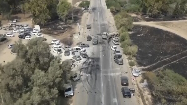 This image from video provided by South First Responders shows charred and damaged cars along a desert road after an attack by Hamas militants at the Tribe of Nova Trance music festival near Kibbutz Re'im in southern Israel on Saturday, Oct. 7, 2023. (South First Responders via AP)